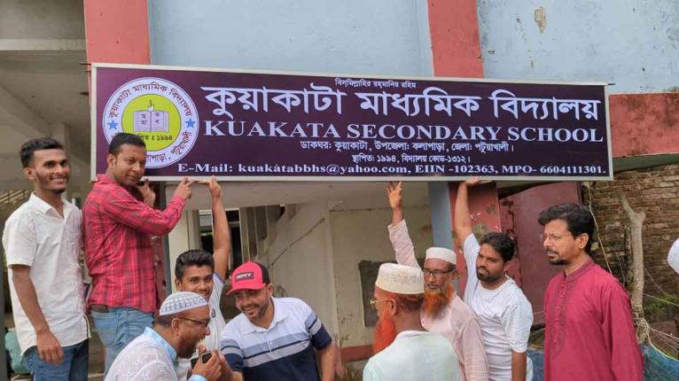 কুয়াকাটা বঙ্গবন্ধু মাধ্যমিক বিদ্যালয়ের পরিবর্তিত সাইনবোর্ড স্থপেনের সময় ছবিটি তোলা হয়েছে।
